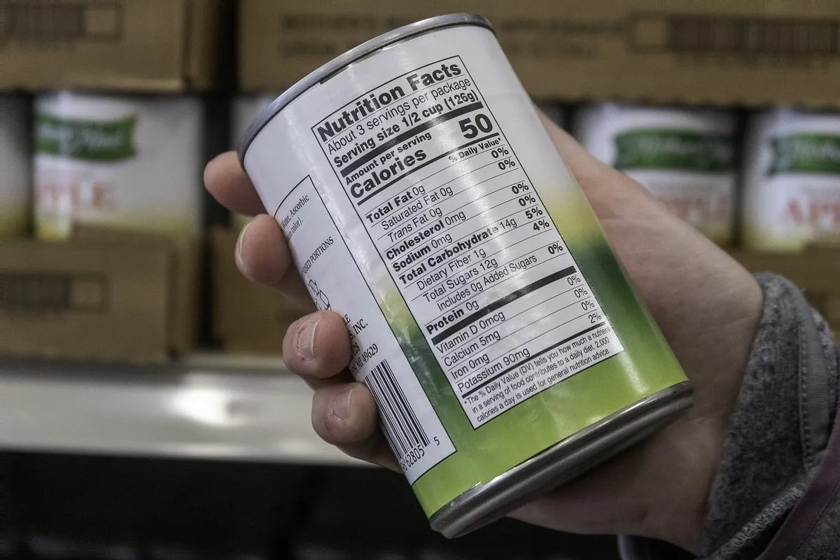 A hand holding a can and reading its label in a food pantry
